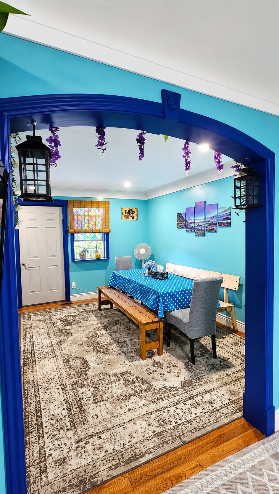 Lounge room dining area seen through a blue arch — table with benches and chairs