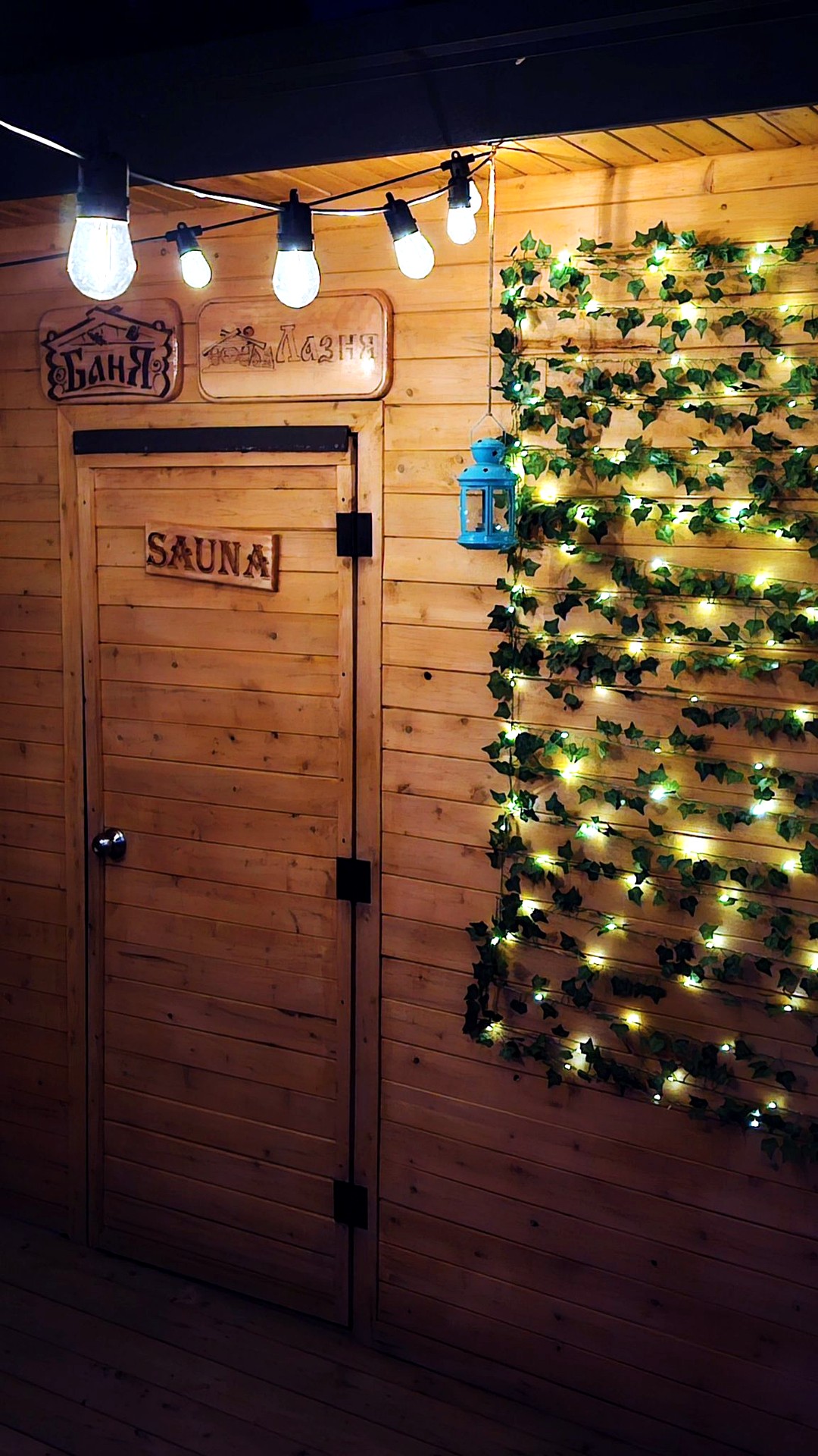 Sauna entrance at night with string lights and Banya, Laznya and Sauna signs
