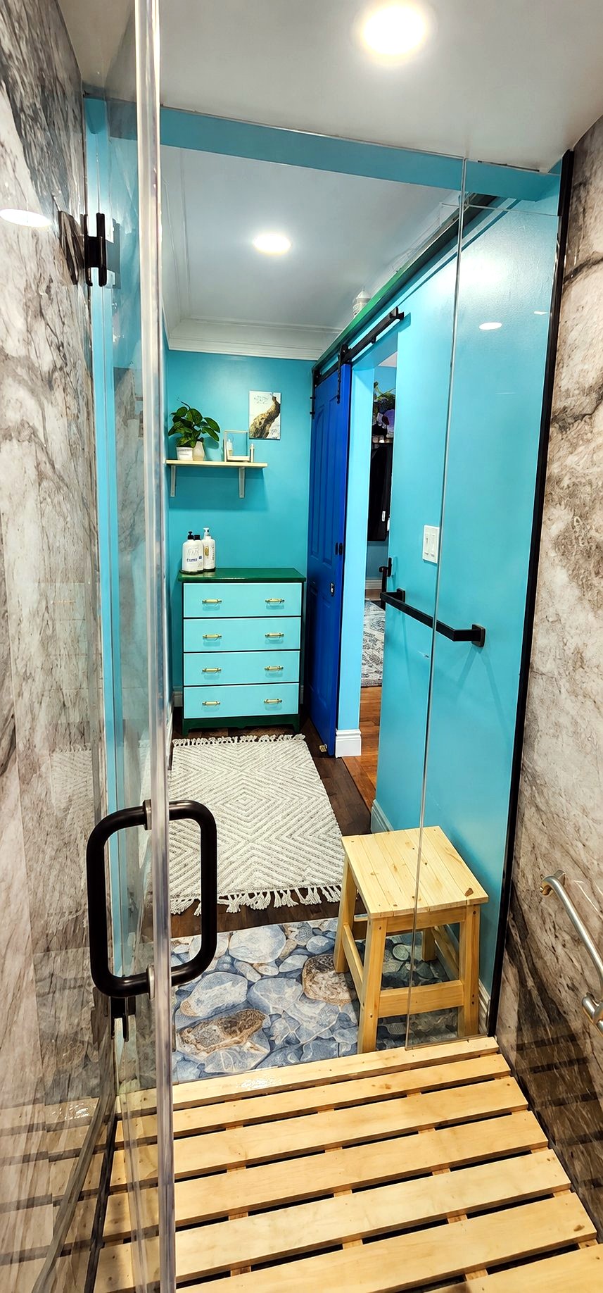 Shower with a glass cabin and turquoise walls at Cozy Place